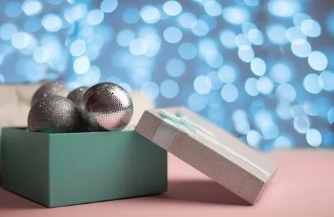 Blue and silver box with silver Christmas balls on the background of blue bokeh Stock Photos