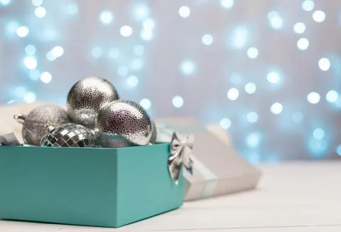 Blue and silver box with silver Christmas balls on the background of blue bokeh Stock Photos