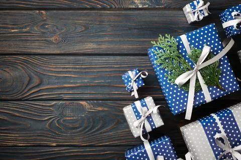 Blue and silver gift boxes with ribbon and thuja on blue wooden background... Stock Photos