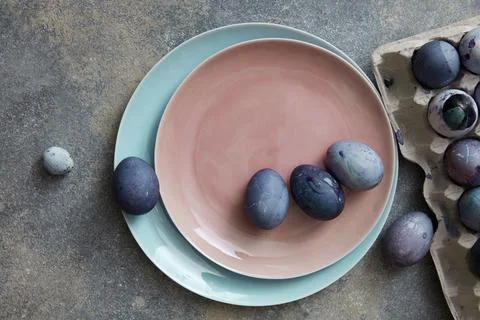 Blue and violet Easter eggs on a ceramic plate in a color of Living Coral P.. Stock Photos