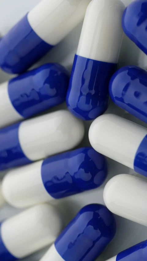 Blue and white capsules shifting in close up pharmaceutical medicine arrangement Stock Footage 345025486