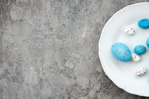 Blue and white easter eggs on plate on a grey plaster background. - Copyspace Stock Photos