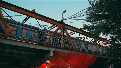 A blue and white passenger train travels across the iconic rusted iron Stock Footage 327629271
