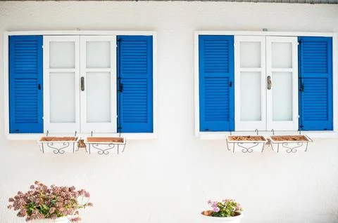 Blue and White Shuttered Windows with Flower Pots Stock Photos