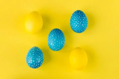 Blue and yellow Easter eggs on bright yellow background, top view 库存照片