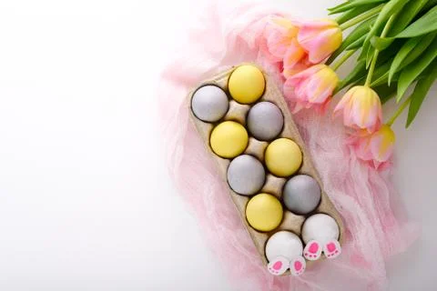 Blue and yellow Easter eggs with pink tulips bouquet, Easter bunnies with pin Stock Photos