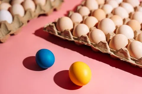 Blue and yellow Easter eggs on pink background with egg cartons Foto stock