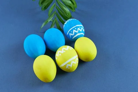Blue and yellow eggs with a pattern on a blue background. Stock Photos