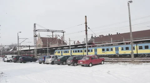 Blue And Yellow Train Arrives To Platform Cars are Parked Two Red Trains Are Stock Footage 59773210