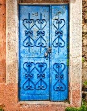 Blue antique door with patterned forging, closed with padlock, against Stock Photos