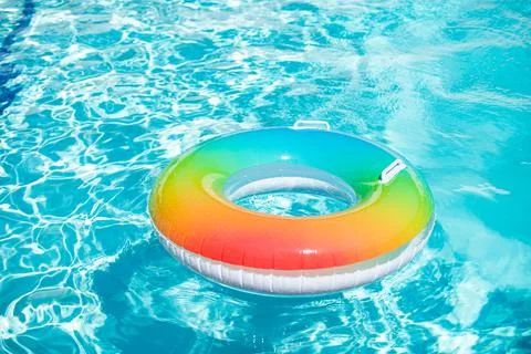 Blue aqua background. Pool float, rainbow ring floating in a refreshing blue Stock Photos