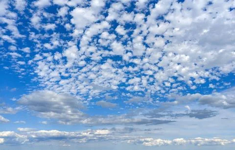 Blue background beneath white clouds. Bright background with cloudscape. Natural Stock-Fotos