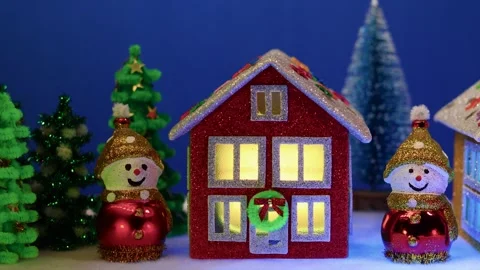 On a blue background, a close-up of a red house between two snowmen Stock Footage 302360003