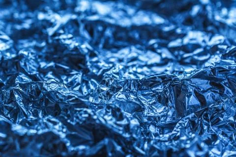 Blue background of crumpled foil. shiny metal foil as a blue background or Stock Photos