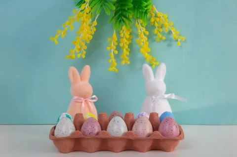 On a blue background, Easter eggs are placed in a container on a table. Pin.. Stock Photos