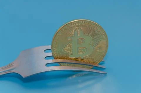 On a blue background, fork and cryptocurrency bitcoin Golden Fotos Stock