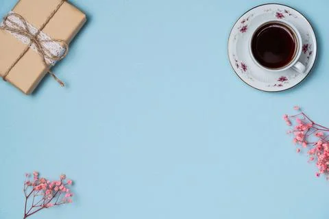 Blue background with gift box, cup of coffee and flowers. Flat lay, top vie.. Foto stock