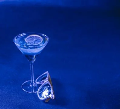 Blue background, mixed drink, lemon, martini glass, yellow sunglasses Stock Photos