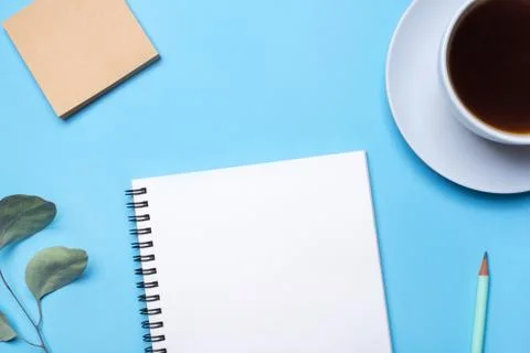 Blue background with notepad, pencil and cup of coffee. Stock Photos