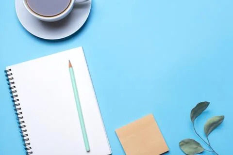 Blue background with notepad, pencil and cup of coffee. Stock Photos