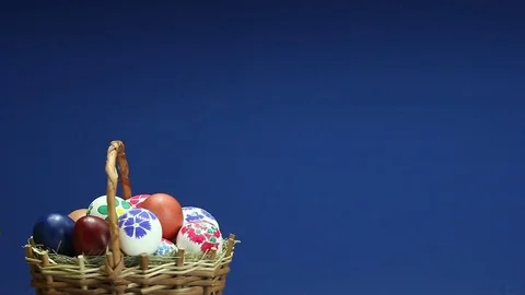 	On a blue background revolves wicker basket with hand-painted Easter eggs Stock Footage 73104450