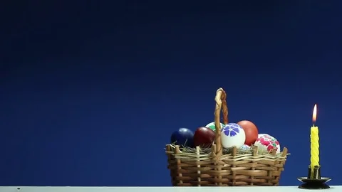 On a blue background revolves wicker basket with hand-painted Easter eggs Видео 73107180