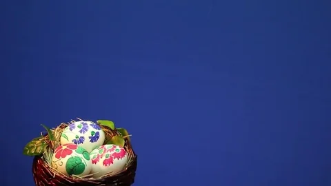 On a blue background revolves wicker basket with hand-painted Easter eggs Stock Footage 73109198