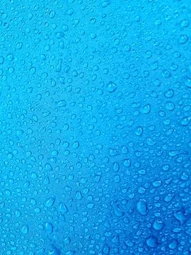 The blue background shows raindrops on a blue fiber waterproof fabric. Stock Photos