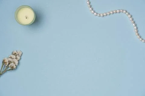 Blue background with string of pearls, candle and flower. Flat lay, top view. Stock Photos