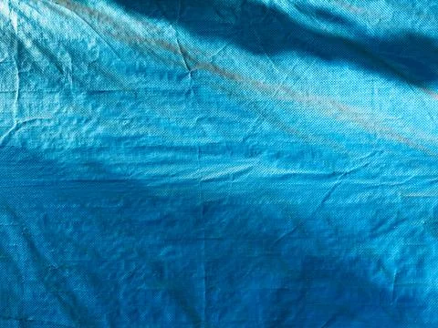 Blue background, texture of fine mesh bundle of braided threads, uneven surface Stock Photos