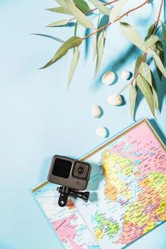 On a blue background there is a world map and an action camera, next to white Stock Photos