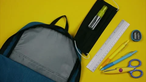 Blue backpack with colored school supplies, a fabric mask and hand sanitizer. Stock Footage 136774280