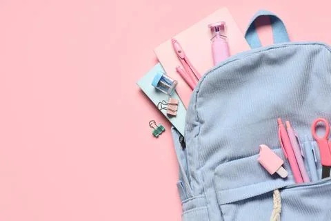 Blue backpack with different stationery on pink background Stock Photos