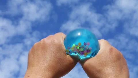 Blue balloon with beads squeezed by hands Video stock 316574280
