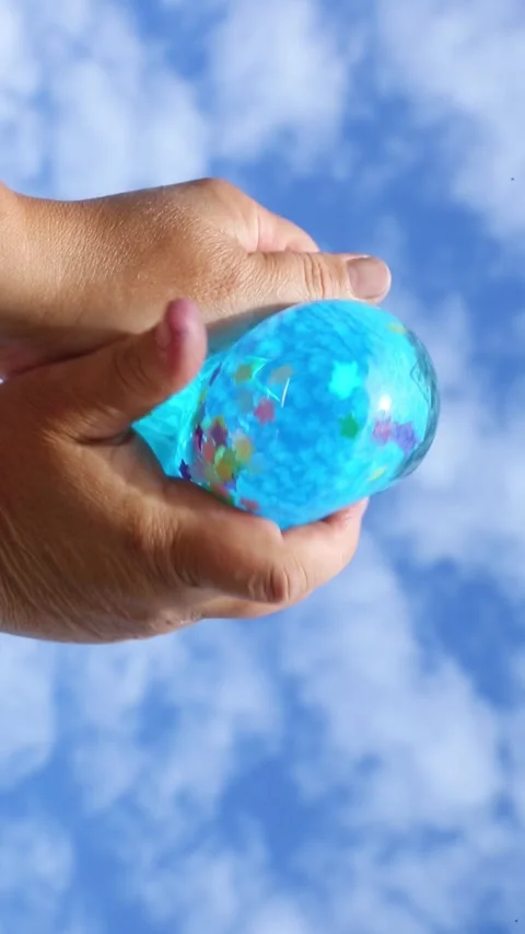 Blue balloon pressed by hands under sky Vidéo 316362574