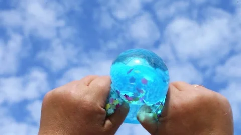 Blue balloon pressed by hands under open sky Stock Footage 318179641