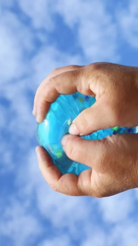 Blue balloon squeezed by hands against sky Stock Footage 321463418