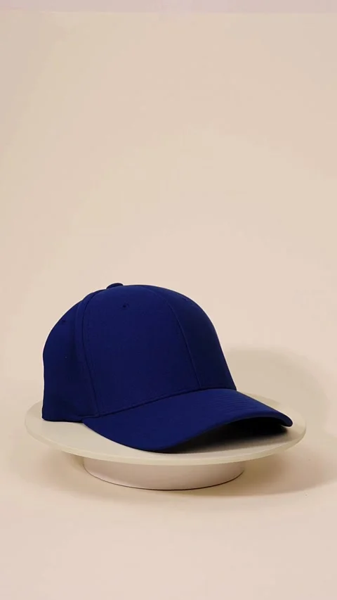 Blue baseball cap rotating on pedestal in studio setting Stock Footage 331774077
