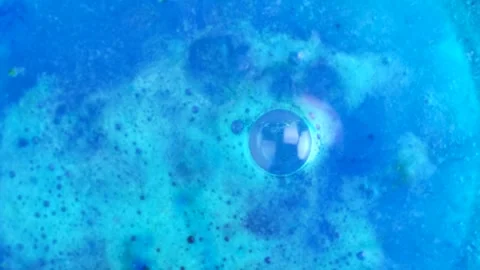 Blue bath bomb ball dissolves in water with bright cobalt blue foam bubbles.. Stock Footage 273675736