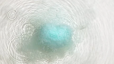 Blue bath bomb ball in the shape of a heart dissolves in water with white foam Stock Footage 270932246