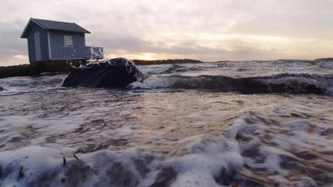 Blue bath cabin and waves breaking against beach at sunset Stock Footage 145870874