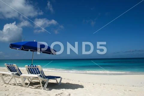 A blue beach chair and umbrella looking out at azure blue waters at Shoal Bay, A Stock Photos