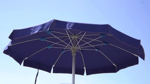A blue beach parasol moving in the wind (slowmotion) Video stock 79037730