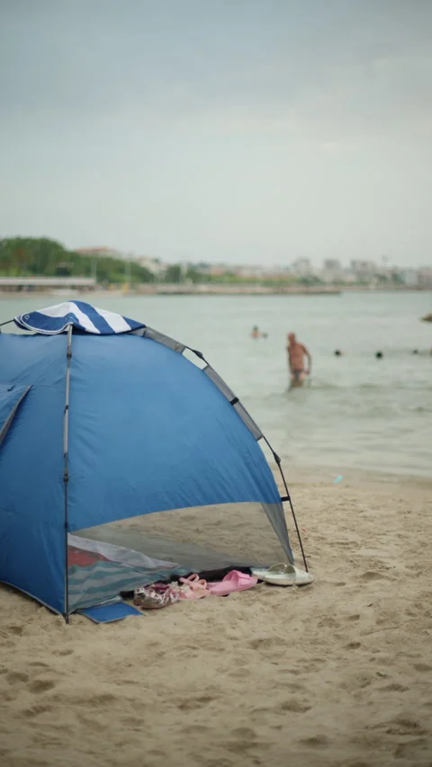 Blue beach tent standing on a sandy beach, offering shade and protection from 動画素材 343118919