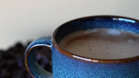 A blue beautiful cup of coffee on a table with coffee grounds on turn table, on Stock Footage 243294971