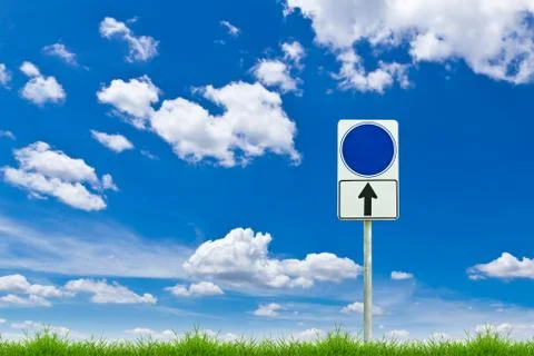 Blue blank sign on fresh spring green grass against blue sky Stock Photos