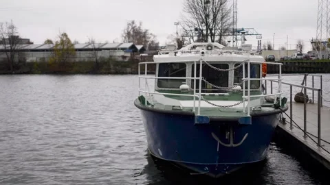 A blue boat on the background of the river is moored to the pier. Stock Footage 256156693