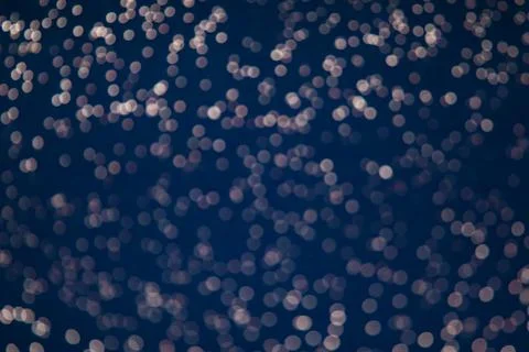 Blue bokeh texture on black background. Dark background with small lights. Stock Photos