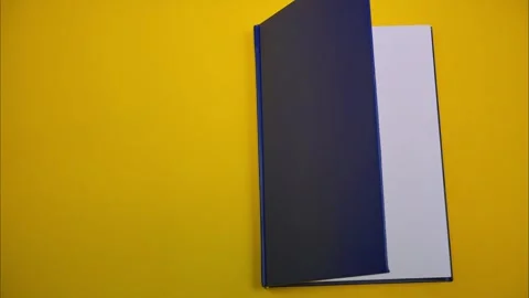 A blue book appears on a yellow background. Stop motion Stock Footage 326168972