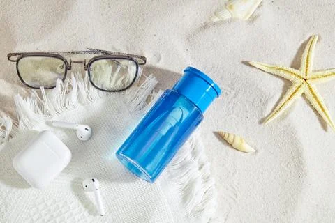 Blue bottle of makeup remover without label, a pair of glasses, airpods and.. Stock Photos